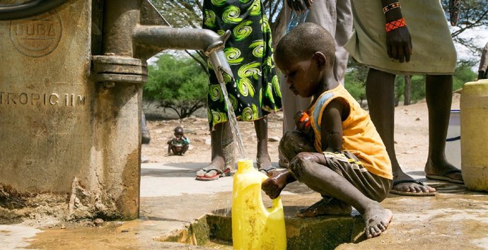 Niño cogiendo agua de una fuente, África