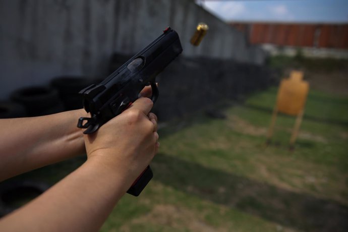 A woman shoots at target during a practice session at a shooting range in Bangko