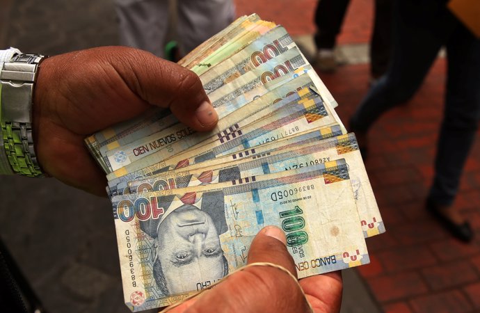 A money changer holds Peruvian Sol bills at a street in downtown Lima, Peru, Dec