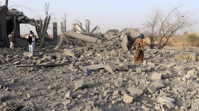 Personas caminan entre los restos de una casa destruida en Saada