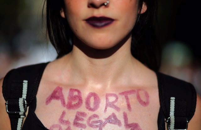 A woman shows the words "Legal abortion" written on her chest during a demonstra
