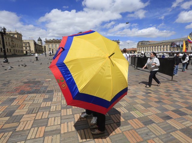 Voters walk while carrying an umbrella with the color of the Colombian flag afte