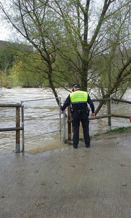 Un agente supervisa el cierre de las pasarelas peatonales por la crecida del río