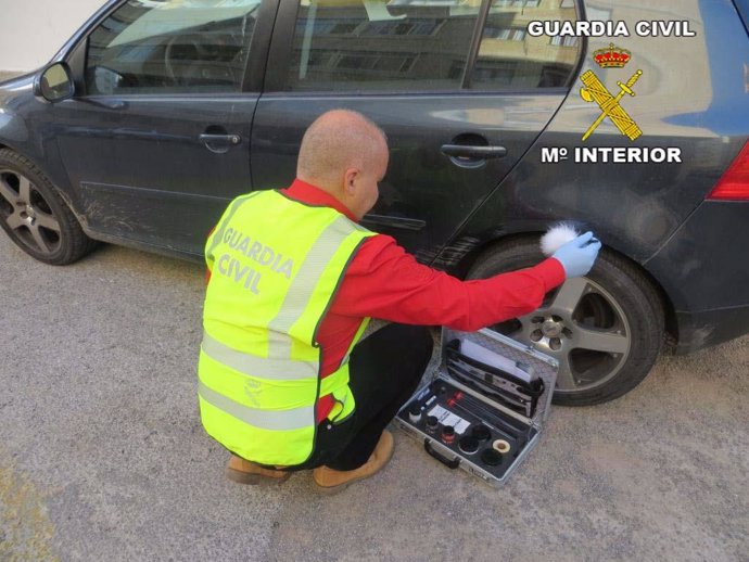 Un agente de Guardia Civil examina un vehículo dañado