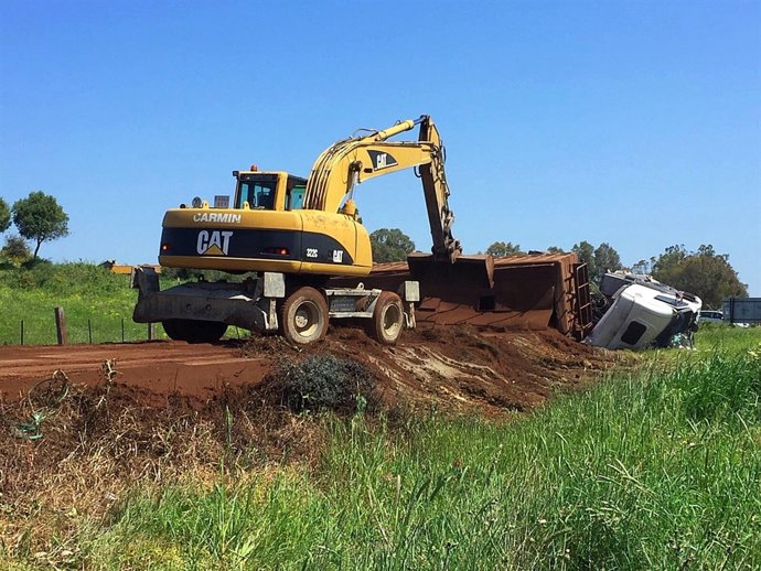 Operarios trabajando tras volcar un camión de cenizas en Los Barrios