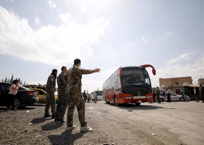 Rebeldes sirios y sus familias salen en un autobús del campo de Wafideen