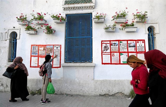 Personas pasan frente a carteles electorales de las municipales en Túnez
