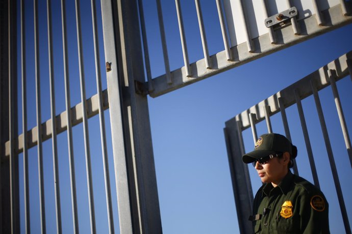 A United States Border Patrol agent keeps watch from a secondary wall separating