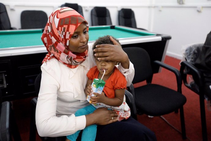 Una mujer de la Cruz Roja con un hijo de un miembro de Estado Islámico