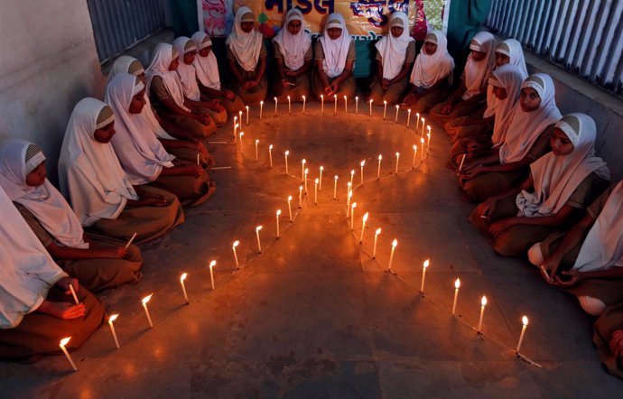 Niñas junto a velas con forma de lazo en el Día Mundial del Sida