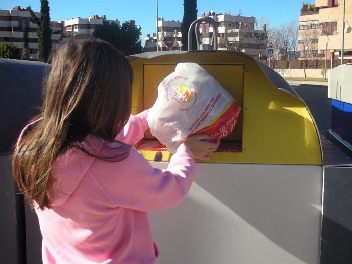 Joven deposita una bolsa de residuos de plástico en un contenedor amarillo