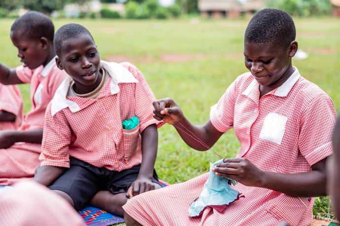 Un niño ayuda a niñas a fabricar compresas en un taller de Plan International