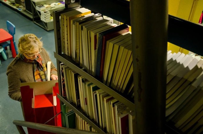 Una mujer lee un libro en una biblioteca