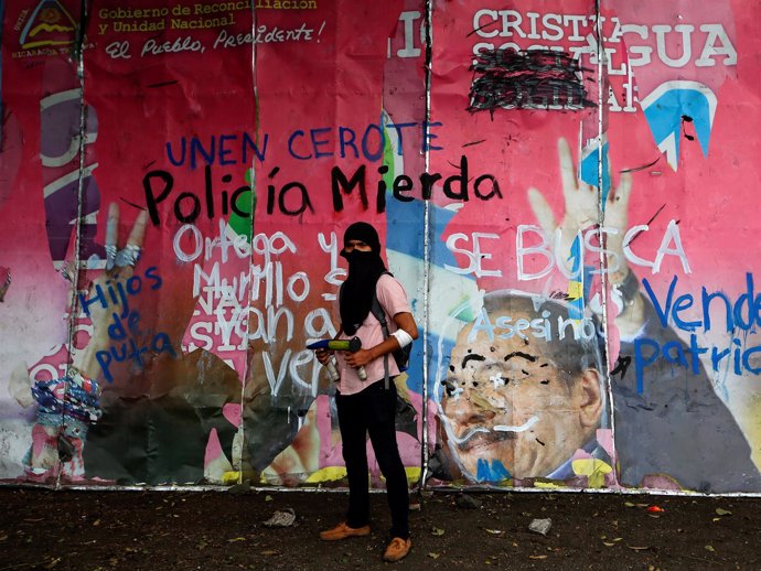 Manifestante ante un mural contra el Gobierno y la Policía de Nicaragua