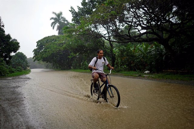 Un hombre monta en bicicleta por un camino inundado por 'Alberto' en Cuba