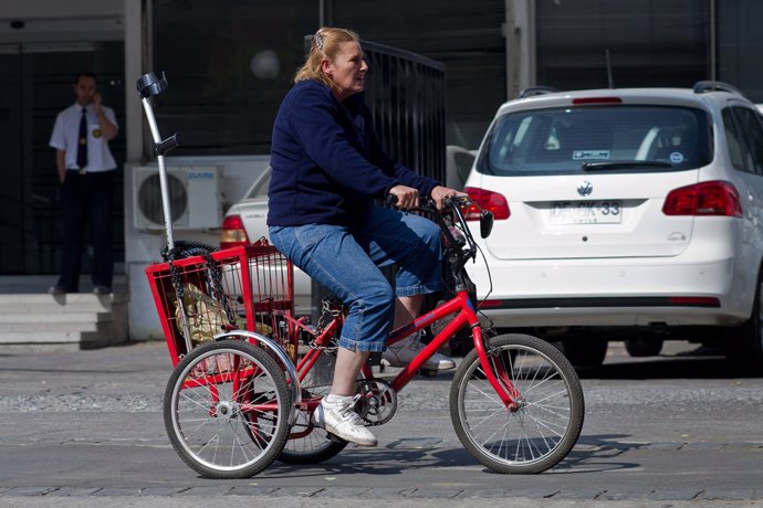 Mujer en bicicleta y con una muleta