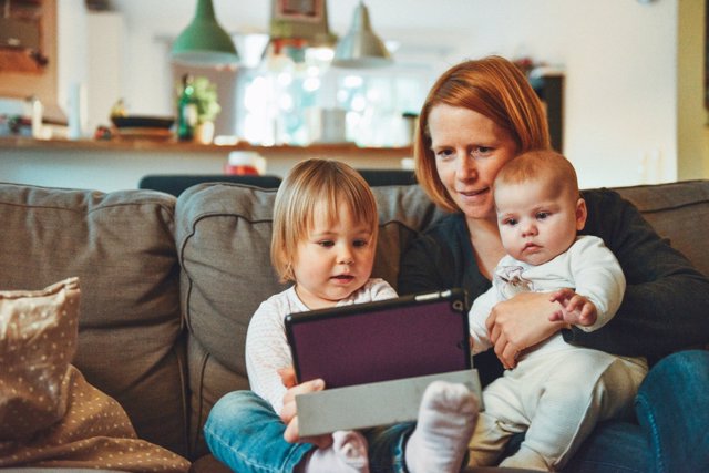 Mujer con sus dos hijos usando una tableta 
