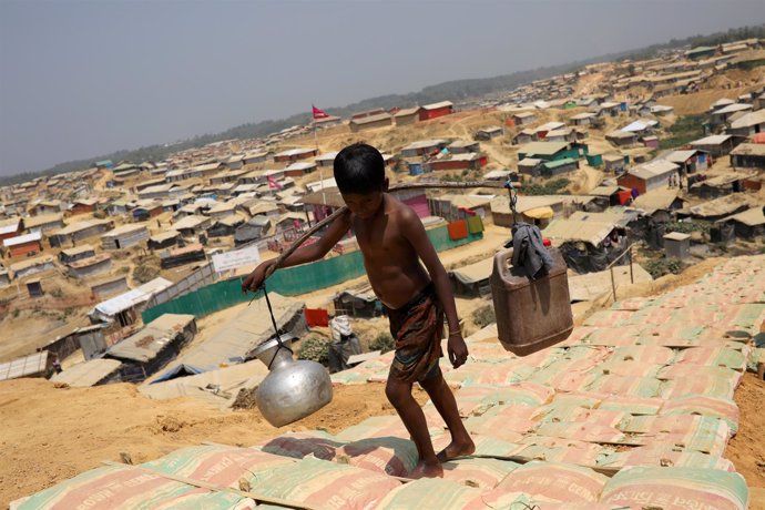 Un niño rohingya transporta agua en un campo para refugiados en Bangladesh