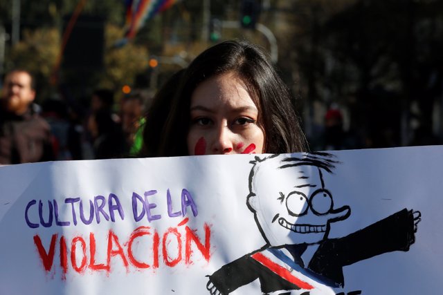 A demonstrator holds a banner reading "Culture of the rape" during an anti-gover