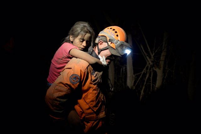 A rescue worker carries a child covered with ash after Fuego volcano erupted vio