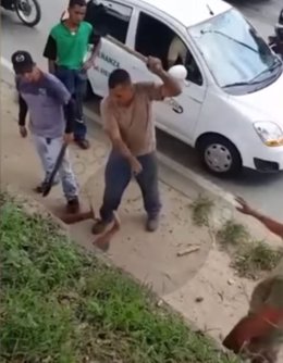 Hombre golpeando a otro con un palo