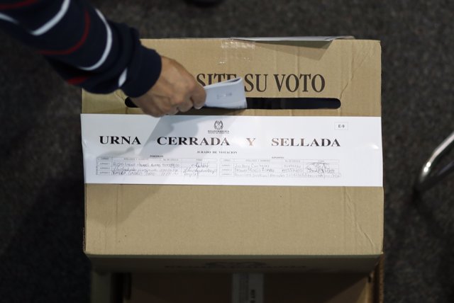 A man drops his ballot into a box at a polling station set up at a convention ce