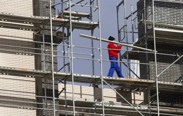 A construction worker carries a plank during works on an unfinished apartment bl