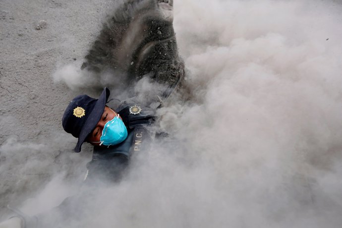 Un policía se tropieza mientras corre por la erupción del Volcán de Fuego