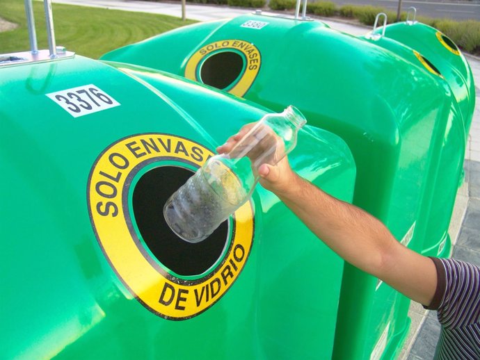 Ciudadano reciclando vidrio en el contenedor verde