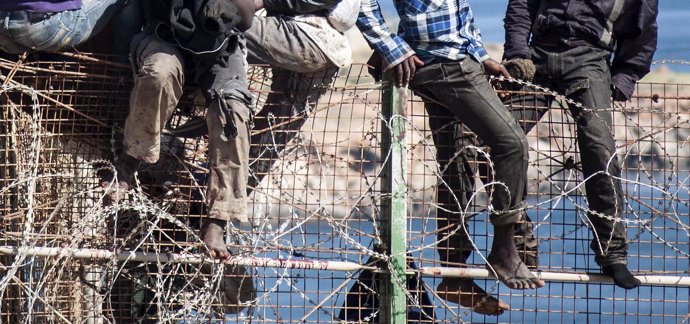 Inmigrantes africanos encaramados a la valla de Melilla con concertinas