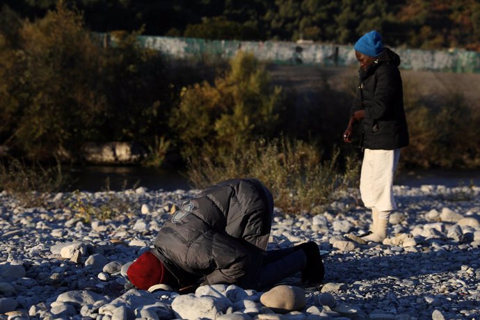 Un hombre reza en la orilla de un río en Ventimiglia antes de cruzar a Francia