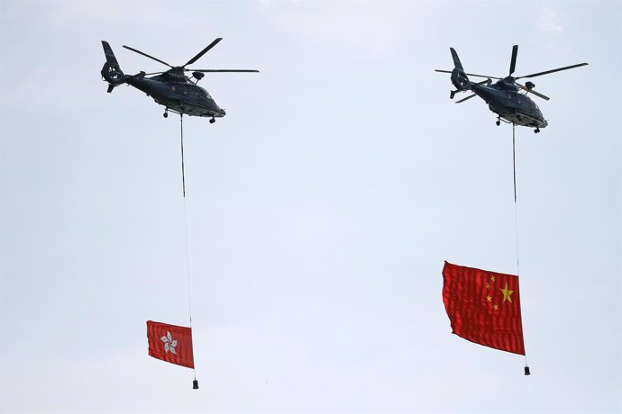 Helicopters carry China's and Hong Kong's flags over the area where a flag raisi