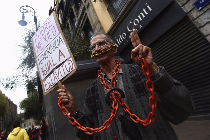 A man holds a poster while wearing chains, during a march marking the 46th anniv