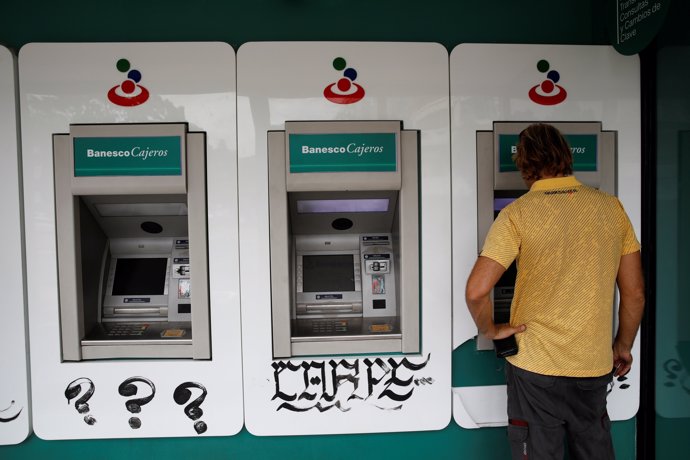 A man uses an automated teller machine (ATM) at a Banesco bank branch in Caracas