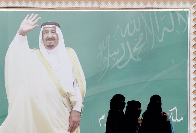 Mujeres ante un cartel del rey Salman de Arabia Saudí