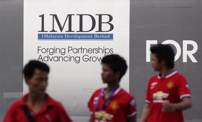 Hombres pasando ante un cartel del fondo 1MDB en Kuala Lumpur