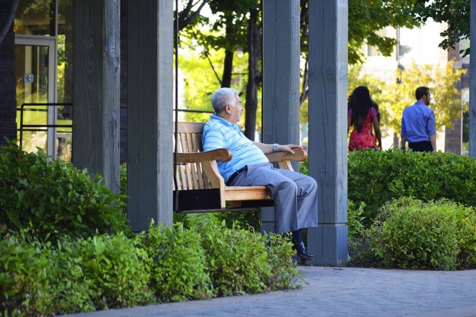 Un anciano descansa en un banco