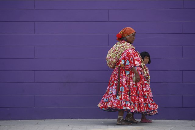 A woman and a girl from the Tarahumara ethnic group walk along a sidewalk in Ciu