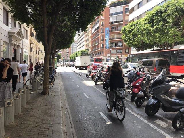 Una mujer en bici por un carril bici en la calle Colon de València
