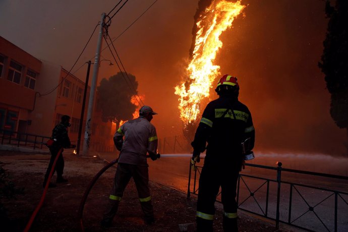 Bomberos y soldados intentan apagar un fuego cerca de Atenas