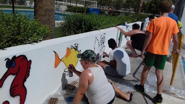 Un grupo de jóvenes pintando el mural de la piscina de Partaloa.