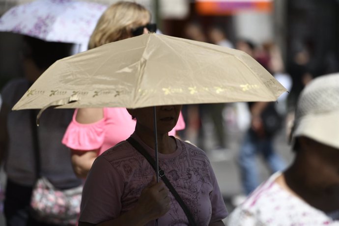 Mujer con paraguas para protegerse del sol (Imagen de archivo)