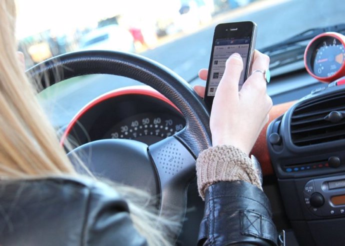 Una mujer usa su teléfono móvil mientras conduce