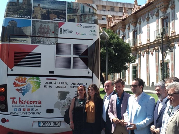 Autoridades posan junto a la publicidad en la parte trasera de un autobús