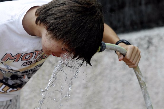 Un chico se refresca con agua