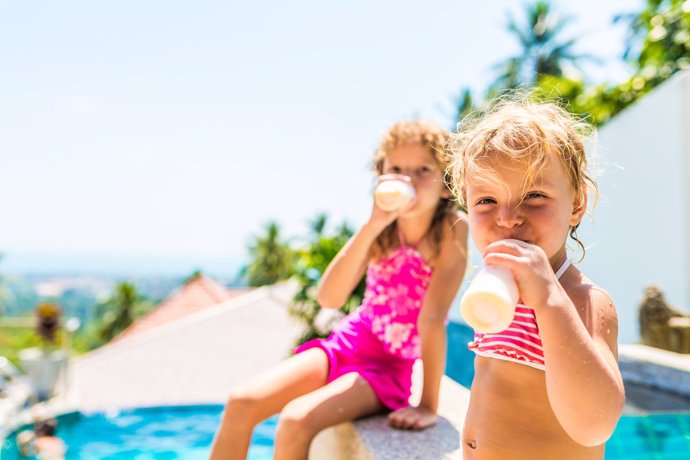 Hambre en la piscina, dos niñas bebiendo yogur, verano, vacaciones
