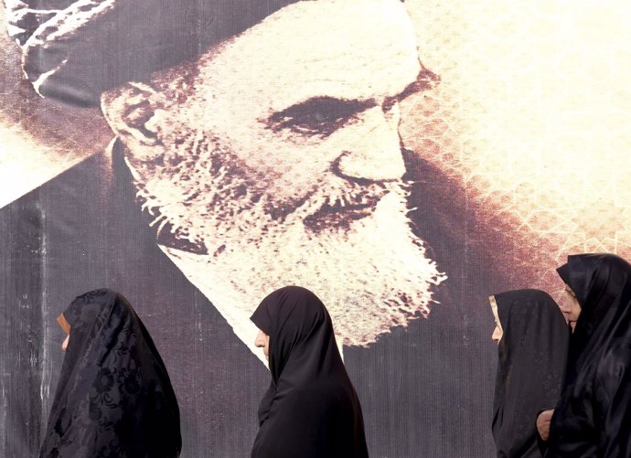 Mujeres iraníes junto a un cartel con el rostro del difunto ayatolá Jomeini