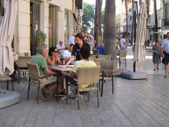 Camarera atendiendo una mesa en un bar de Málaga.