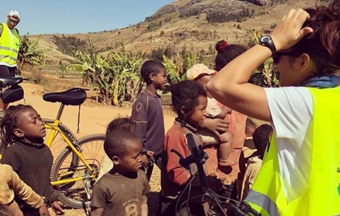 Una de las ciclistas de 'Roul mon Coco' con niños de Madagascar