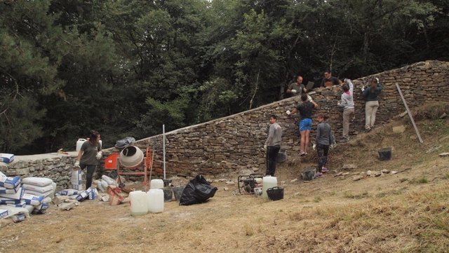 Jóvenes y monitores trabajan en el afianzamiento de un muro    